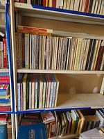 Shelf with a variety of vintage vinyl record albums and music books including visible titles and various sizes.
