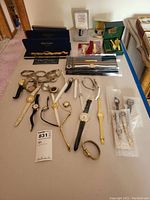 Wide view of the assortment of women's watches laid out on a table including boxed sets, metal, and leather strap watches.