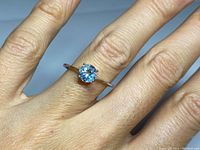 Ring on finger showing size and appearance of aquamarine gemstone in white gold setting, minimal surface wear visible.