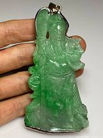 Front view of green jade warrior figure pendant in sterling silver bezel, held in hand