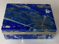 Top view of rectangular lapis lazuli box showing deep blue surface with white and grey matrix and silver rim