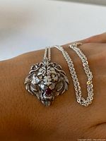 Close-up of sterling silver lion's head pendant necklace with genuine ruby, showing detail of lion's face and ruby.
