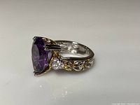 Side profile view showing pear-shaped amethyst and clear accent stones with filigree band