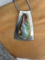 Front of pendant showing boulder opal set in brushed sterling silver with visible surface wear and tarnish.
