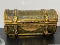 Front view of closed gilt bronze snuff box showing domed lid, applied straps and latch details