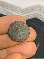 Reverse side of the coin showing a seated figure holding an object