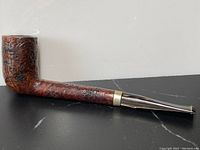 Side profile of the antique Stanwell burl pipe showing textured wood bowl and stem, metal band, and black mouthpiece.