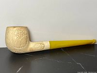 Side view of the full pipe showing meerschaum bowl and amber stem with carved floral and grape designs.