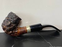 Left side view of antique burl wood pipe showing textured bowl and shank, black stem, and sterling silver band with hallmark and signature.