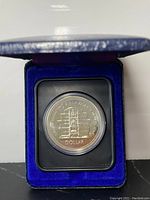 Silver Canadian silver dollar coin in original protective case within a blue velvet-lined display box.