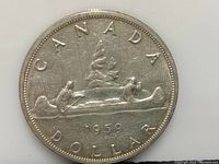 Reverse side of the 1959 Canadian Silver Dollar showing the voyageur design with two men paddling a canoe, date 1959, and inscriptions CANADA DOLLAR.