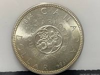 Front side of 1964 Canadian Silver Dollar showing floral emblem and text CHARLOTTETOWN QUEBEC 1864 1964 CANADA DOLLAR.