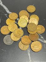 Photo showing multiple Canadian tombac nickels scattered on a dark surface, coins with visible wear and tarnish.