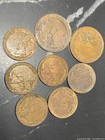 Eight coronation coins with Canadian map and heraldic shield on one side, worn patina bronze coloring.