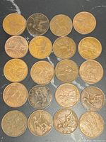 Top-down image showing twenty bronze British pennies arranged in rows, varying in patina and surface wear.