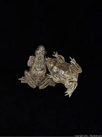 Two antique brass frog findings shown from back and front, highlighting hollow backs and surface details
