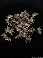 Multiple brass and silver-toned elephant-shaped findings with prongs scattered on a black surface.