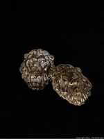 Two close-up lions head findings showing detailed facial features and brass finish
