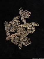 Cluster of several brass filigree findings with detailed openwork against a black background.