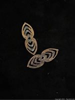 Photo of two medium-sized antique brass findings with symmetrical openwork design on black background.