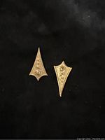 Two individual antique brass Art Deco style geometric findings shown on a black background highlighting their hollow backs and raised dots