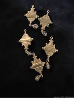 Four antique brass findings each with one Swarovski crystal, displayed against a black background