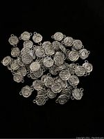 Multiple antique metal rose pendant findings displayed together on a black background.