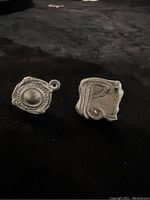 Pair of two unique unfinished metal earrings with posts and closed jump rings for accent attachments on a black background