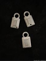 Two close-up pendants showing rectangular shape with circular hanging loop and unfinished surface detail