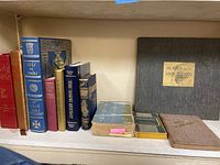 Front view of antique books arranged on shelf including Holy Bible, readers digest, LIVRE DE CANTIQUES, Moods of the Mountain, and History de S. Philomena