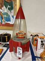 Full view of the antique Carlton Rocket bubble gum machine with red rocket design and original label.
