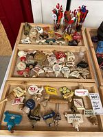 Top-down view of a large set of vintage liquor pourers organized on wooden tray and colorful drink stirrers in jars at rear