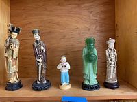 All five Asian figurines arranged side by side, showing different styles and colors