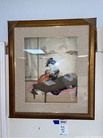 Full view of framed shadow box showing geisha figure inside the frame wearing colorful kimono and seated at a writing table.