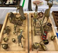 Two trays holding 20 brass figurines and decorative brass items including lamp parts and candle holder.