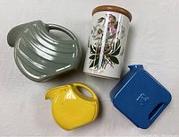 Four pottery items arranged on white surface: two Hotpoint ice water pitchers, yellow creamer, floral canister.