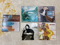 Five Joni Mitchell albums laid out on a flat surface showing the front covers, each with distinct artwork including nature, portrait, and vintage imagery.