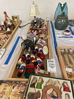 Nutcracker ornaments, figurines, small train, and lighthouse lamp with figurine and ballet slipper on a wooden tray.
