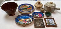 Overview image of all ten pottery pieces arranged together showing variety of shapes, colors, and sizes