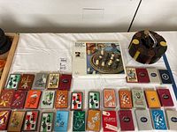 Full view displaying Rosenthal Quatripola board game box, 32 packs of vintage playing cards arrayed in rows, and a circular wooden poker chip holder with chips.