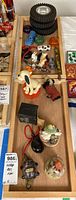 Overview showing stacked black Krishna tires, small toy cars, wind-up toys including dogs, and yo-yos in orange and green.
