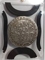 Obverse view of medal in acrylic holder showing naval scene and rim inscription