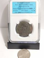Obverse of coin in plastic slab with US quarter for scale