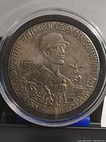 Front of 1939 German commemorative coin showing soldier and workers relief in plastic holder, highlighting inscriptions and details