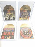 Photo of four KISS band die-cut cards with album cover fronts and gold-colored record shapes.
