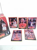 Overview of metal tin and all five signed Michael Jordan cards arranged on surface