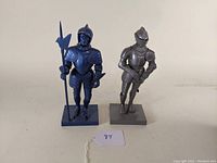 Two vintage plastic model figures of suits of armor, one blue and one gray, displayed side by side on a flat surface.