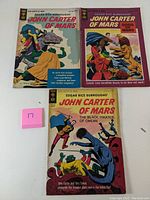 Three John Carter of Mars comic books from Gold Key, issues #1, 2, and 3, displayed face up showing covers.