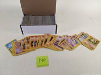 Box of over 140 vintage Pokemon trading cards with cards fanned out.