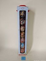 Set of 7 Disney Christmas ornaments in original blue Disney Store box with snowflake designs and window showing all ornaments arranged vertically.